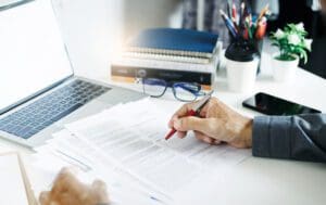 Businessman working on laptop reviewing document reports reading