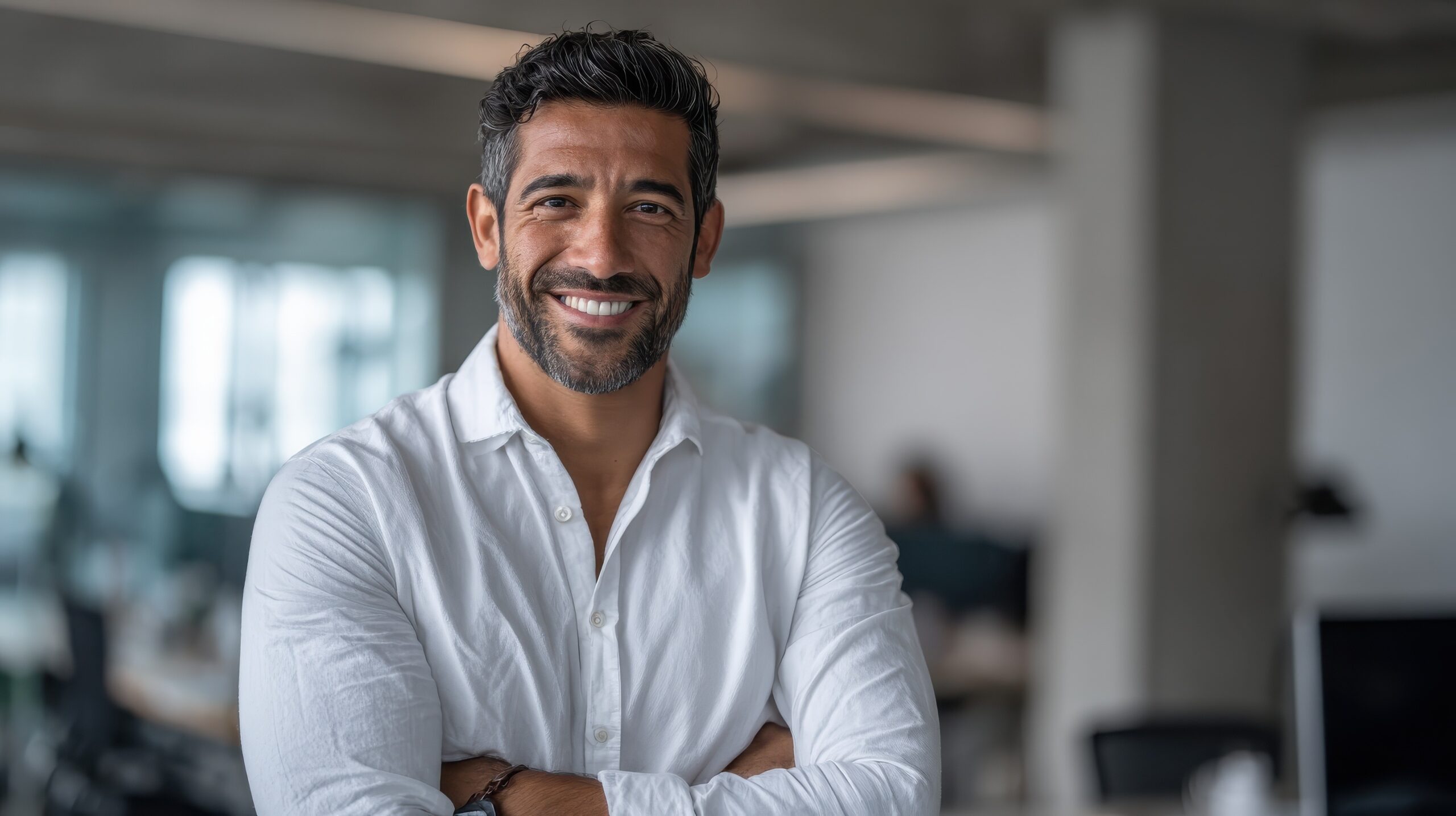 Smiling confident Latin Hispanic businessman CEO standing in modern office looking at camera Middle Eastern professional leader and entrepreneur