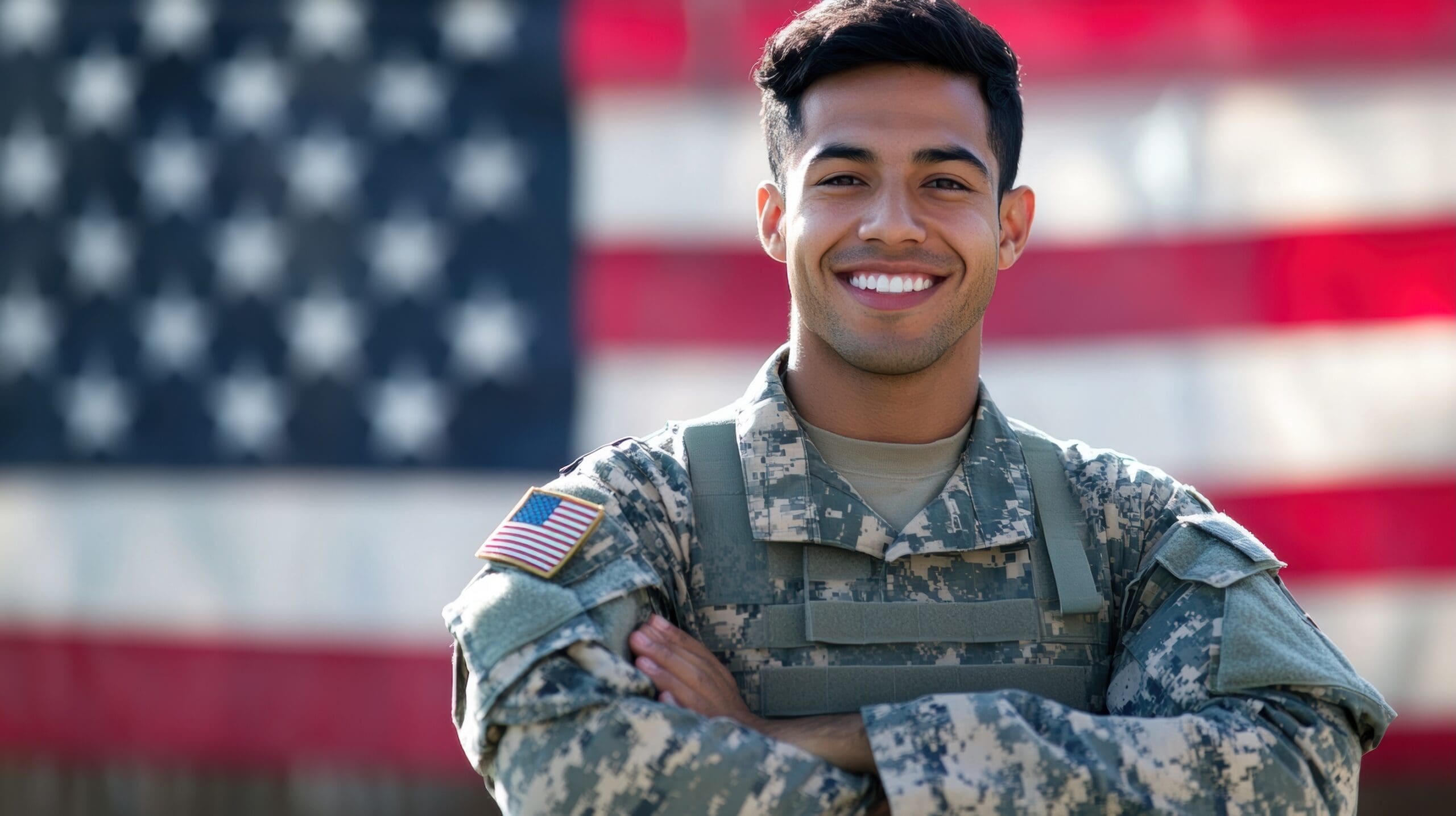 Portrait of smiling Hispanic soldier in camouflage uniform with American flag background.