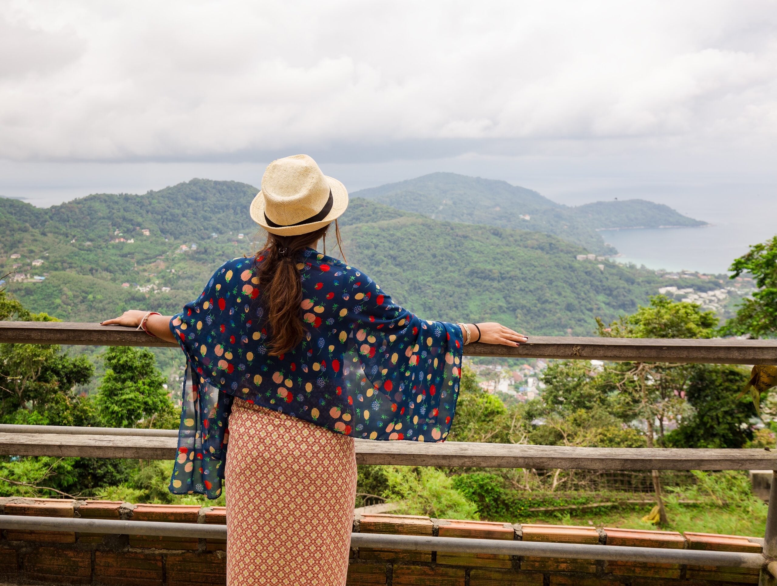 The girl looks from a height at a beautiful view. Girl in a hat and a bright scarf.