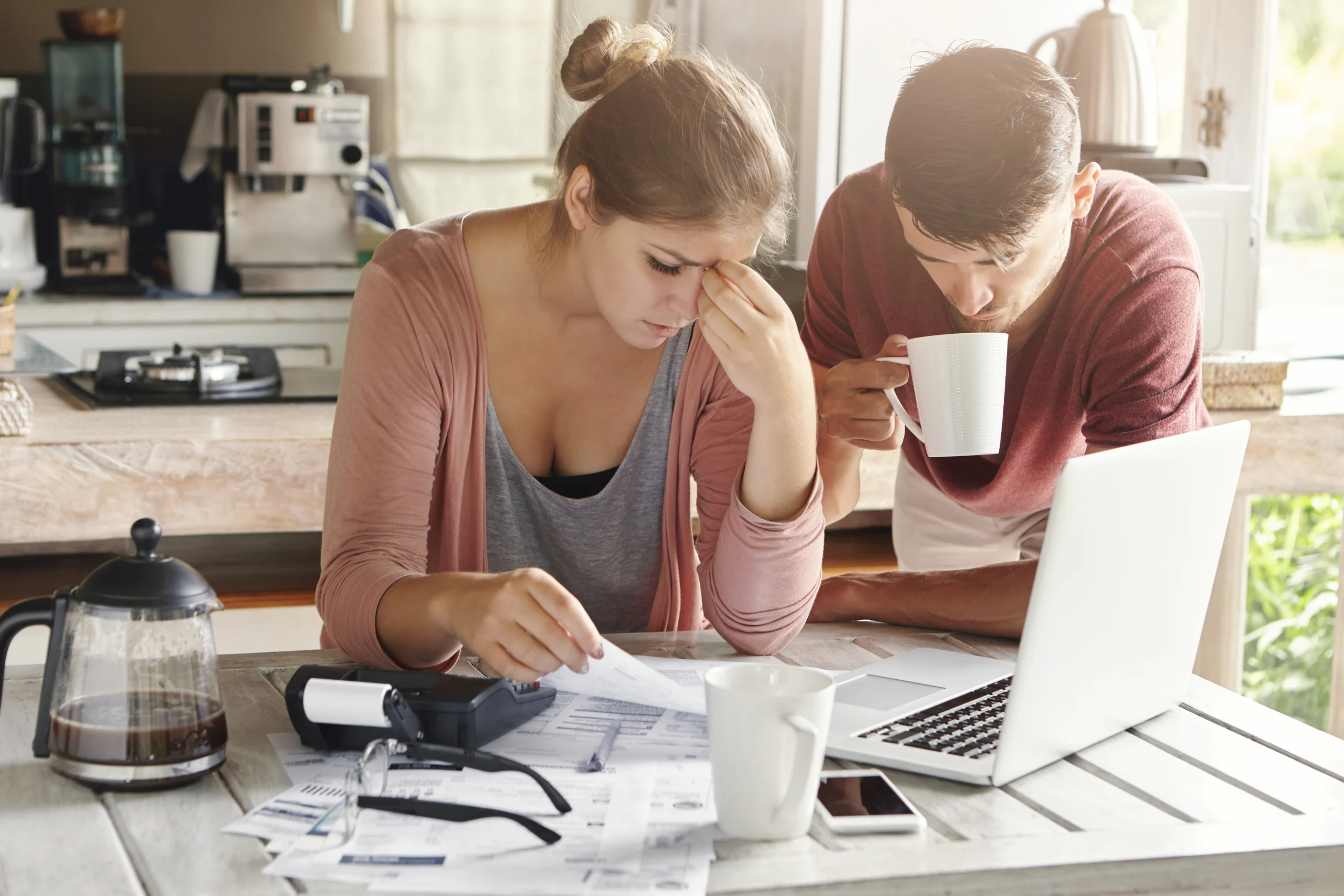couple-facing-financial-problem-failing-pay-loan-bank-stressed-woman-managing-family-budget-making-calculations-using-laptop-calculator-her-husband-standing-her-with-cup-tea